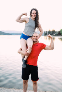two athletes flexing muscles in front of lake